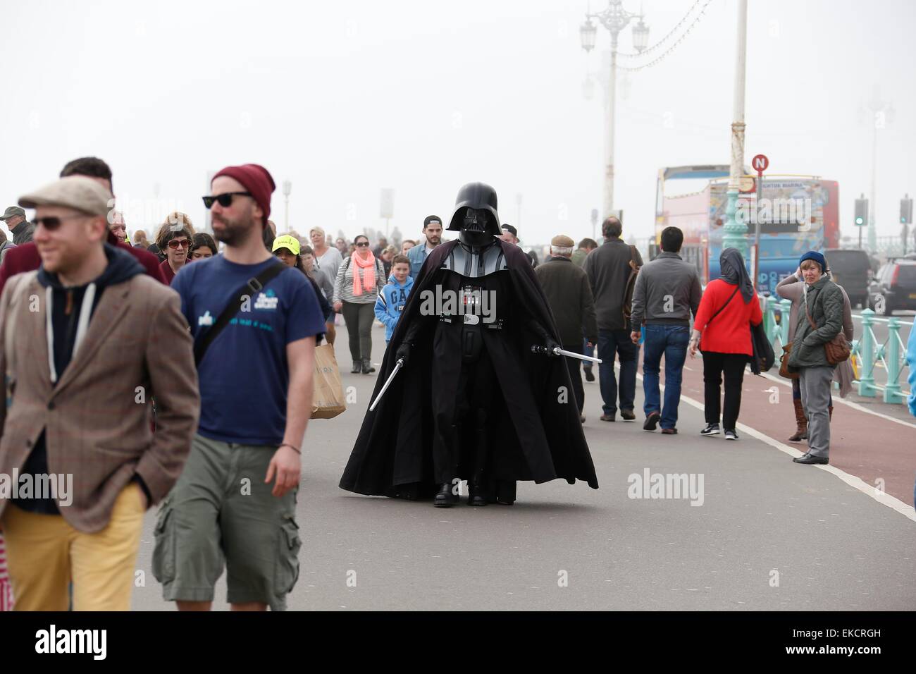 Eine Straße Entertainer gekleidet Anzeige, die Darth Vader entlang Brighton Seafront unter den Massen an einem nebligen Frühlingstag Spaziergänge. Stockfoto