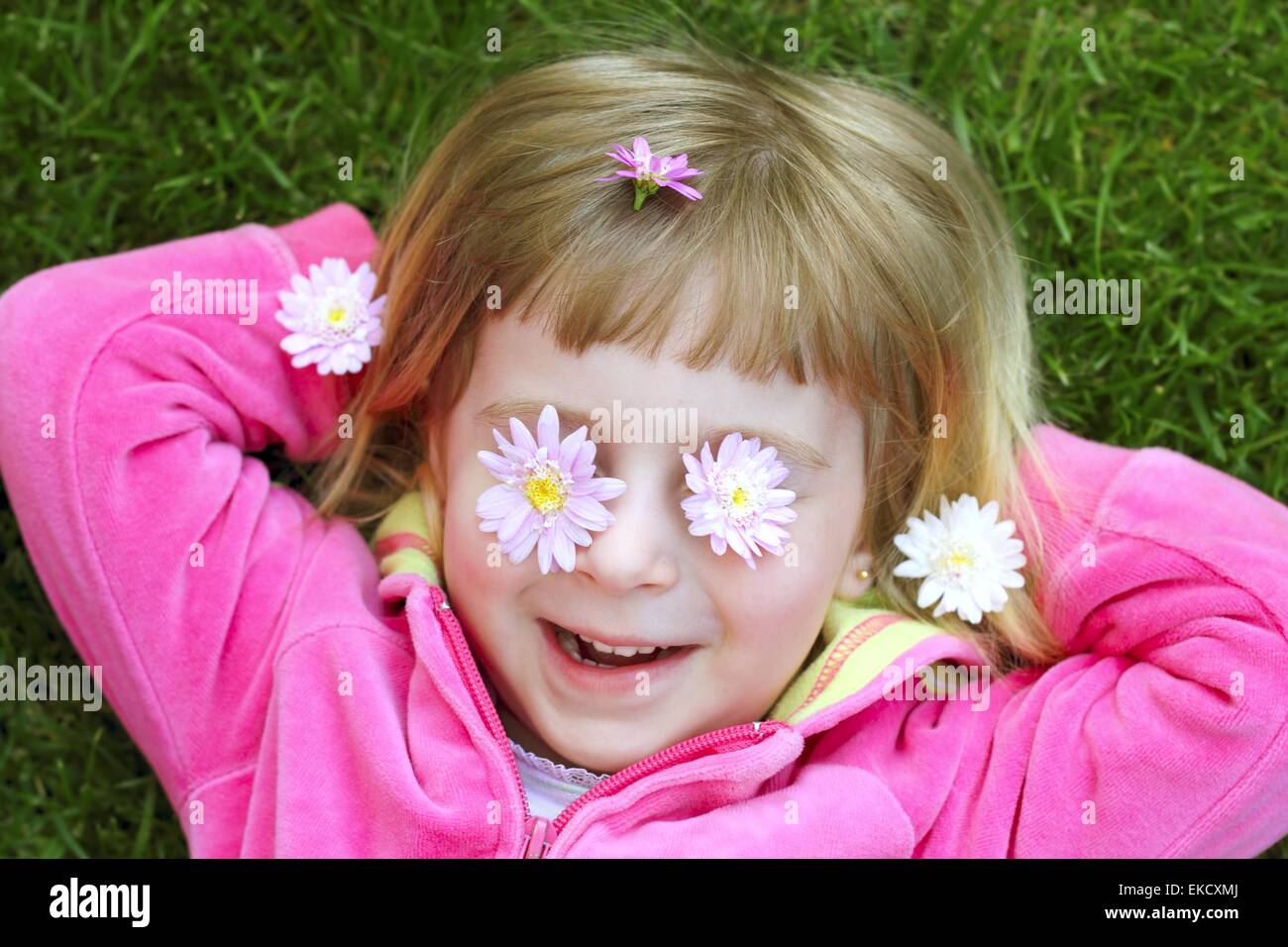 kleines Mädchen verlegen Rasen Daisiy Blumen in Augen Stockfoto