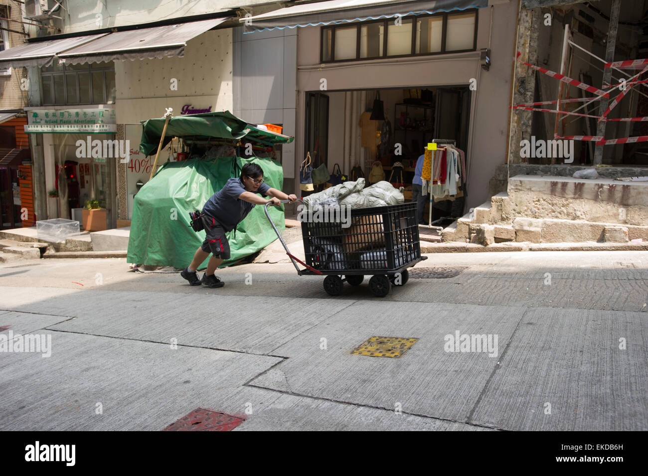 Asiatische Arbeiter Schieben Karren auf einer steilen Straße in Hong Kong Stockfoto