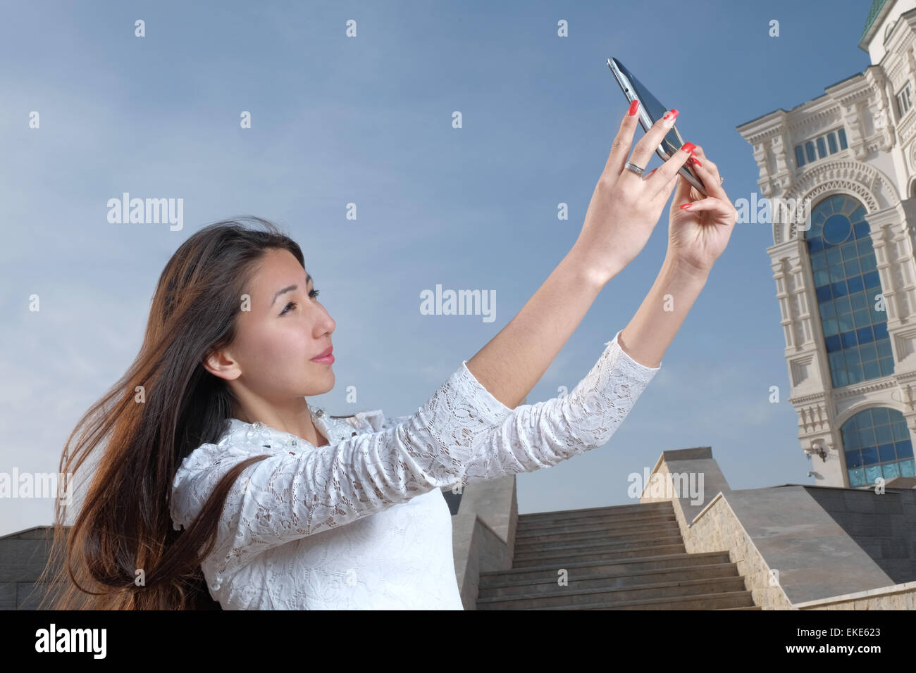 Junge japanische Frauen mit langen Haaren Selfie im City Park Afainst Schritte zu tun und klaren blauen Himmel mit leichten Dunst, Exemplar am Himmel Stockfoto
