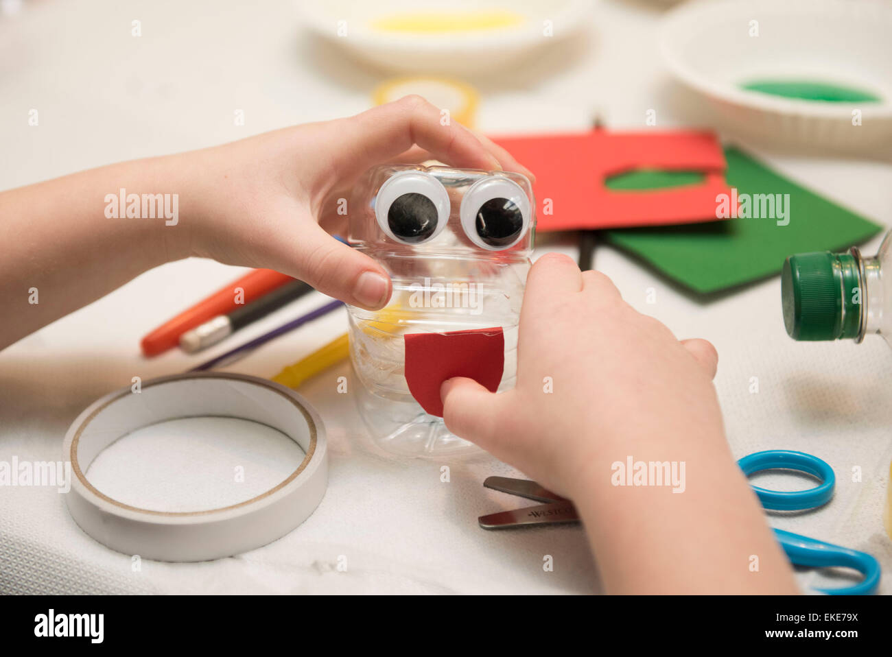 Ein Kind macht eine Spielzeug aus einer Trinkflasche während einer Sitzung in Kunst und Handwerk. Stockfoto