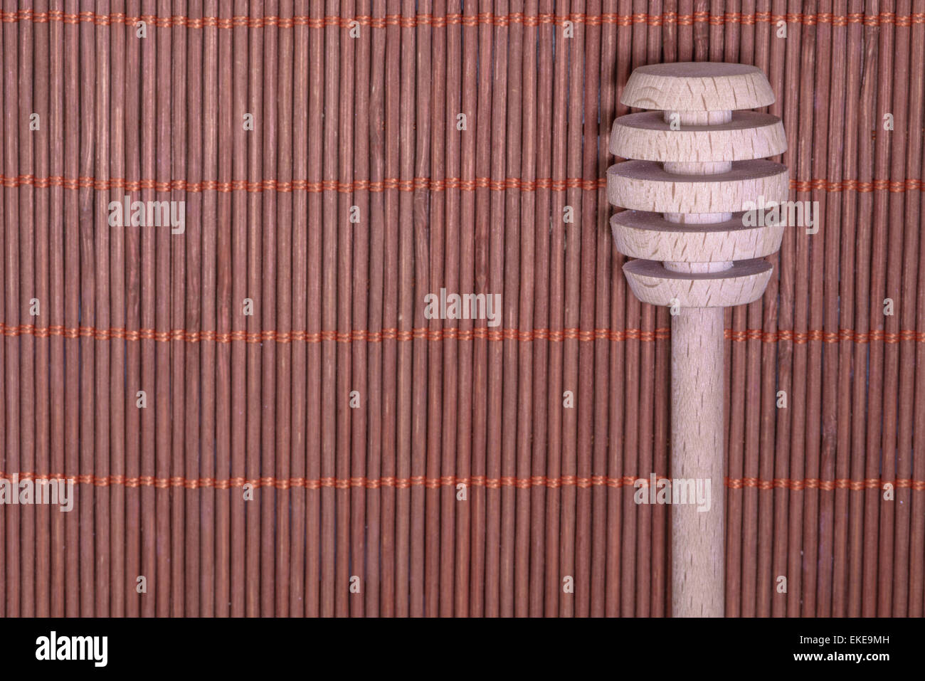 Holz-Honig-Löffel auf einem schönen geflochtenen Teppich als Hintergrund Stockfoto