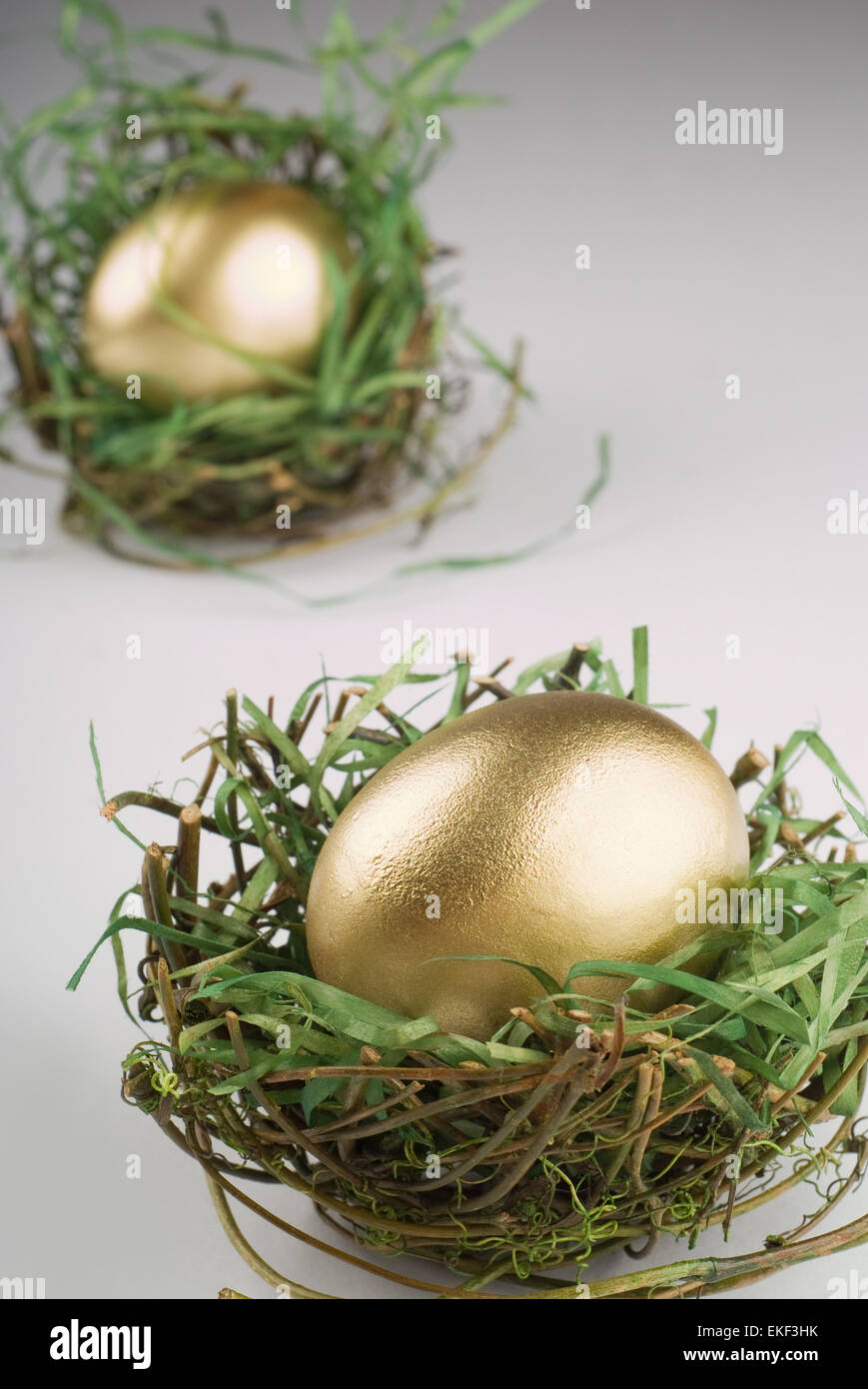 Goldenes Ei im Nest auf grau Stockfoto