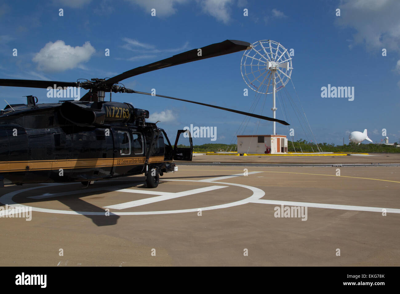 Ein Black Hawk Hubschrauber steht auf einer Landeplattform in Cudjoe Key, Florida, neben dem Tethered Aerostat Radar System (TARS), das für Überwachung und Grenzsicherheit genutzt wird. Stockfoto