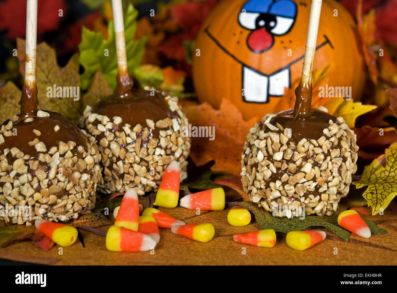 Äpfel mit Karamell mit Süßigkeiten und lustigen Kürbis für Herbst Dekorationen. Stockfoto