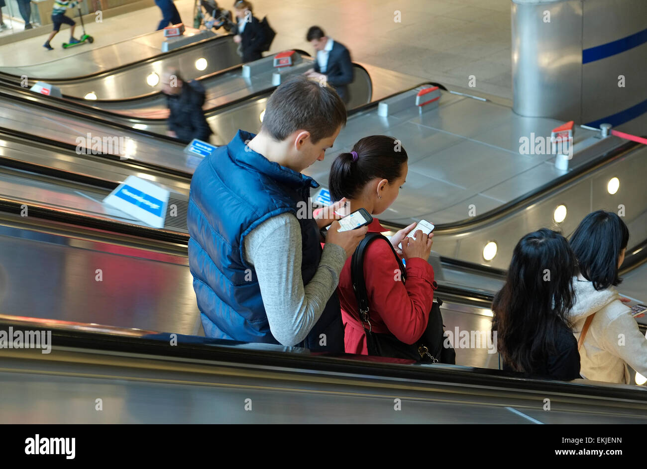 Menschen, die Benutzung von Mobiltelefonen auf beweglichen Rolltreppe, Canary Wharf, London, england Stockfoto