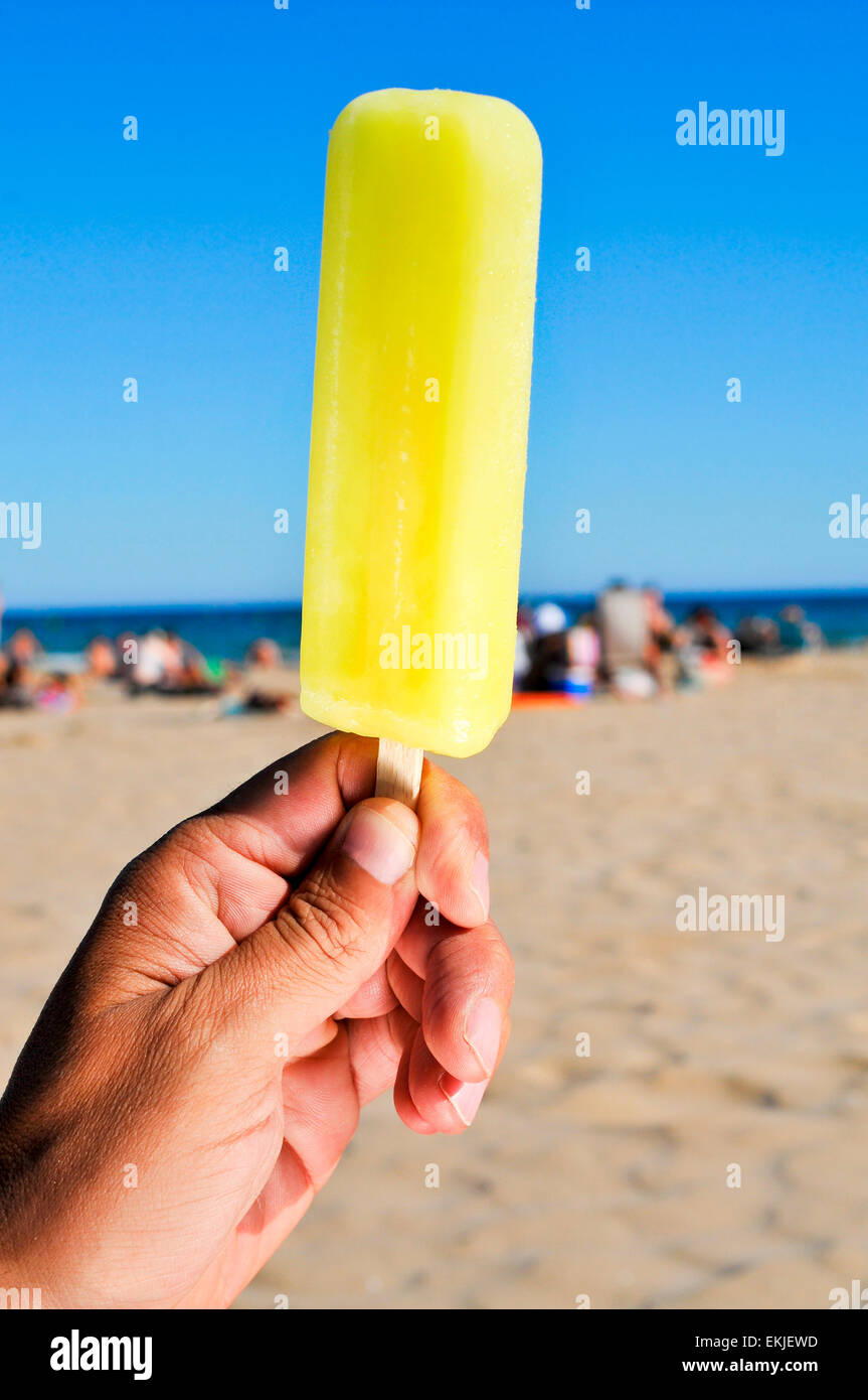 Nahaufnahme eines kaukasischen Jünglings mit einem appetitlichen Eis pop in der Hand am Strand Stockfoto