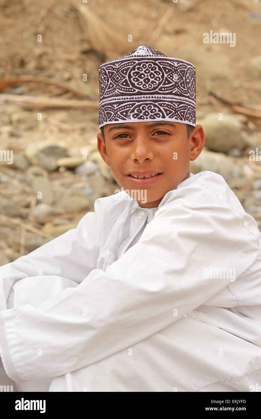 Eine nicht identifizierte omanische junge tragen einer Kummah (traditionelle GAP) entspannt in einem Wadi unterhalb seines Großvaters Datum Plantage. Stockfoto