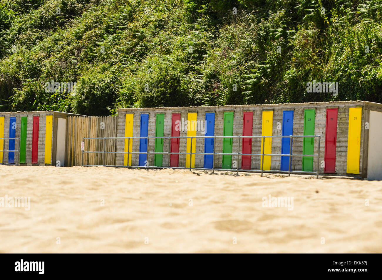 Eine Reihe von bunten Strandhäuschen am Rande eines Sandstrandes. Stockfoto