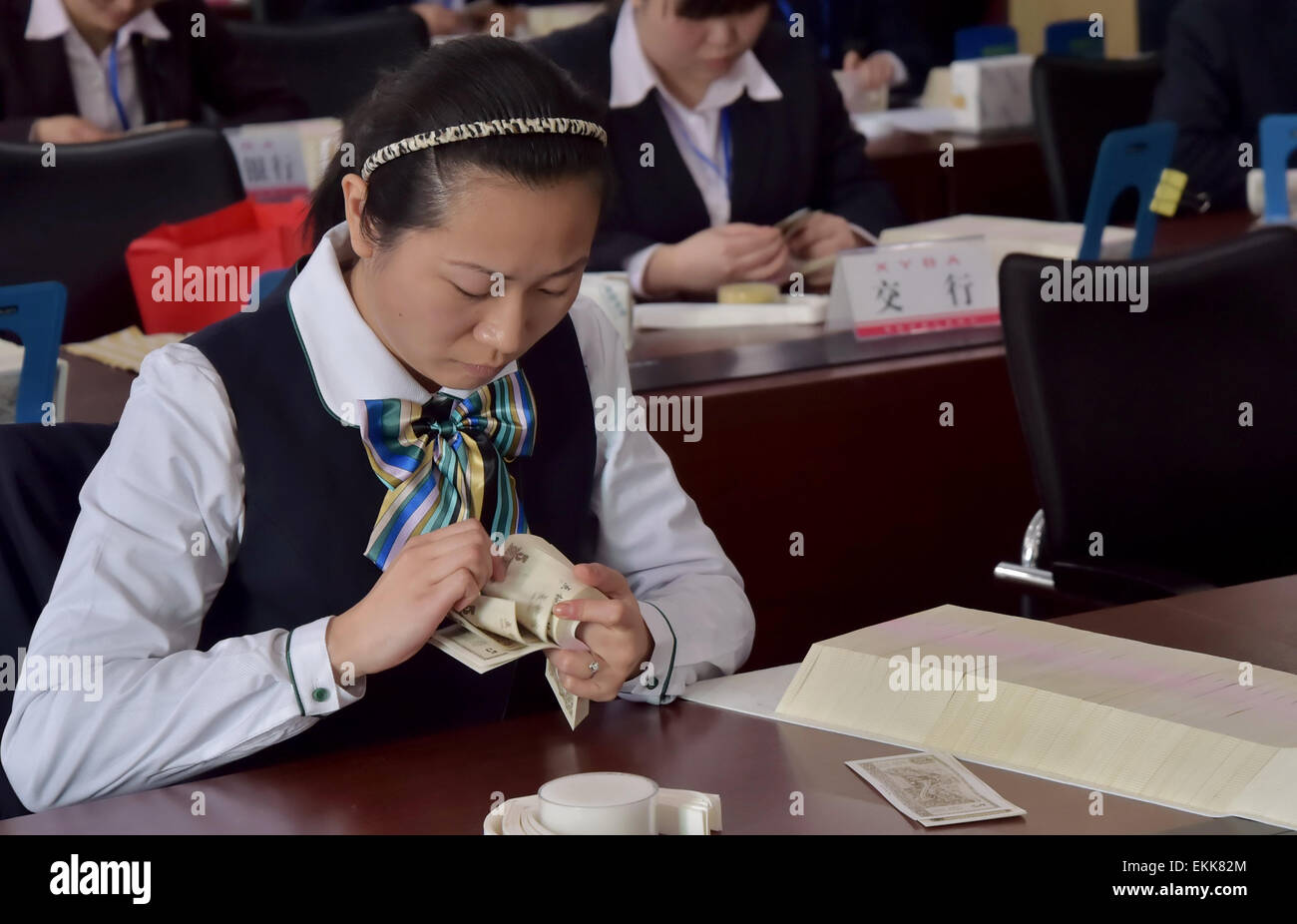 Eine weibliche Bankmitarbeiter zählt Falschgeld auf eine Fertigkeit Spiel in Xiangyang, Provinz Hubei, China am 11. April 2015. Stockfoto