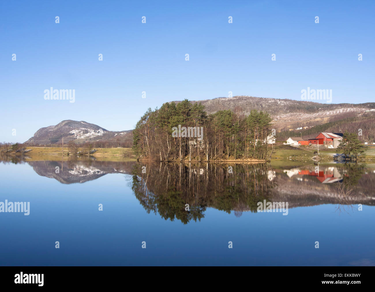 Idyllische Landschaft in Ryfylke, die Fjorde östlich von Stavanger Norwegen, Frühling, Schnee, Sonne und ein Spiegelsee mit einer typischen farm Stockfoto