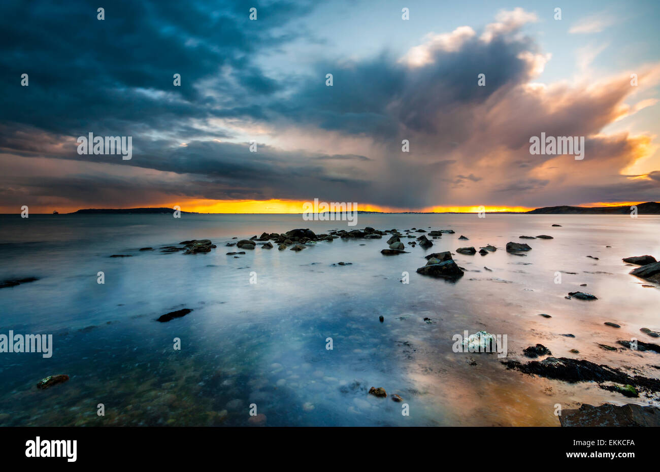 Regen-tragende Wolken hängen über den Horizont Casting Reflexionen in stehenden Gewässern vor der Küste von Dorset Stockfoto