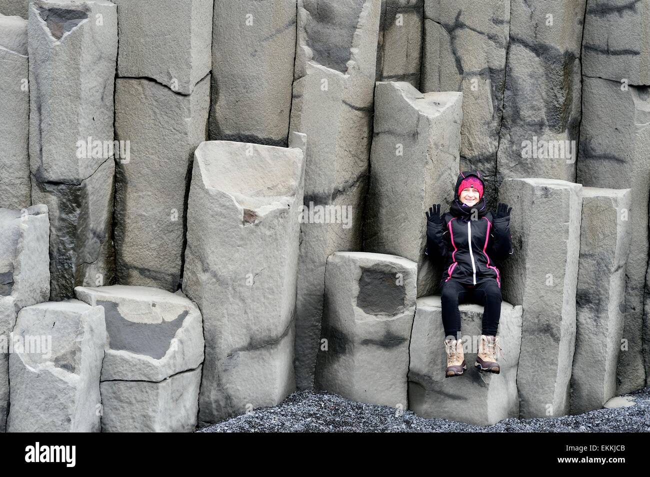 Frau sitzend posiert auf Basaltsäulen Island Stockfoto