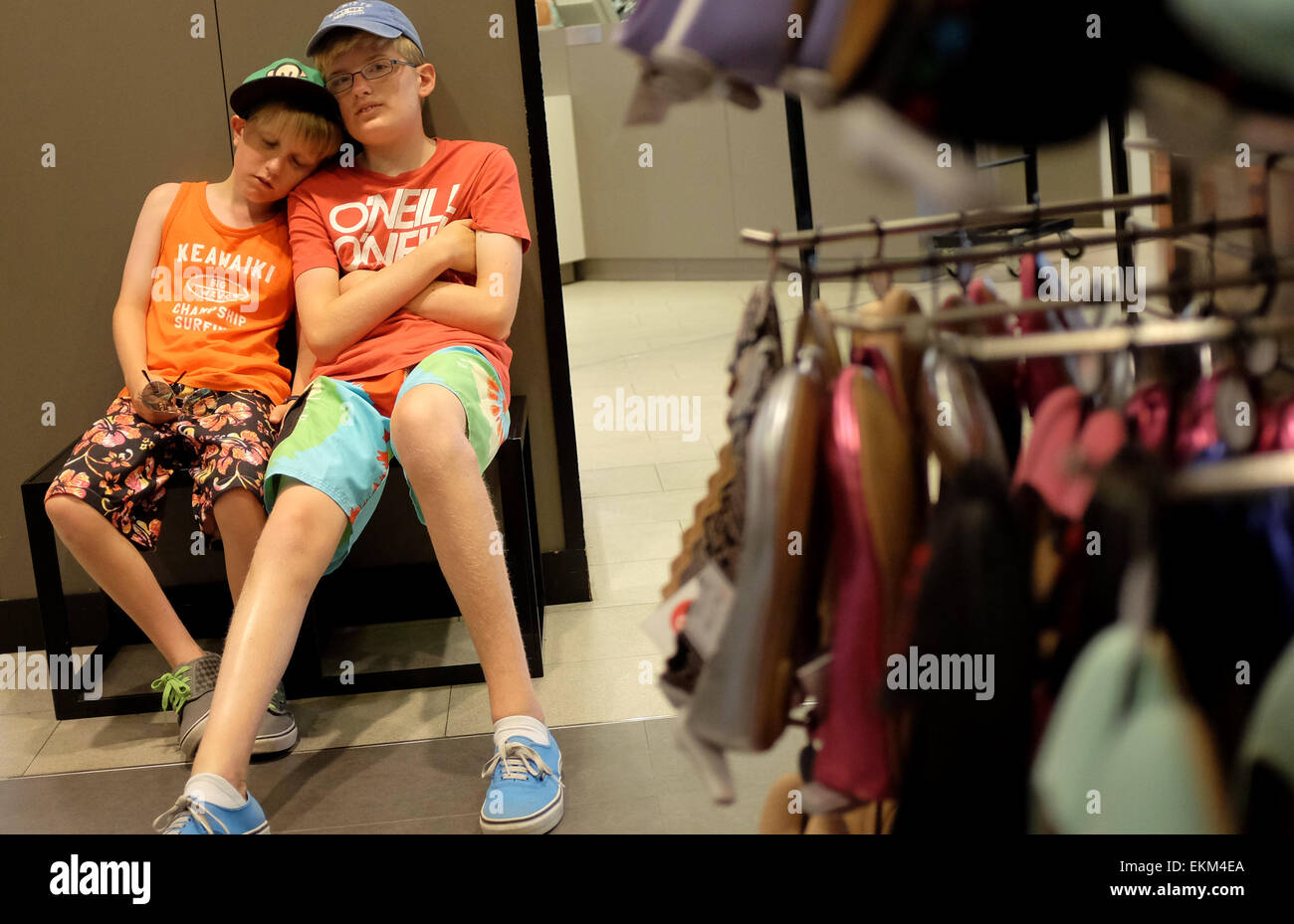 gelangweilte Kinder warten auf ihre Mutter zu beenden in einem Schuhgeschäft einkaufen Stockfoto