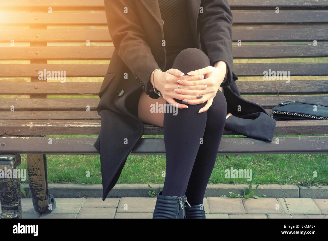 Junge Frau sitzt auf der Bank Teil des Körperbildes Hintergrundbeleuchtung hipster Stockfoto