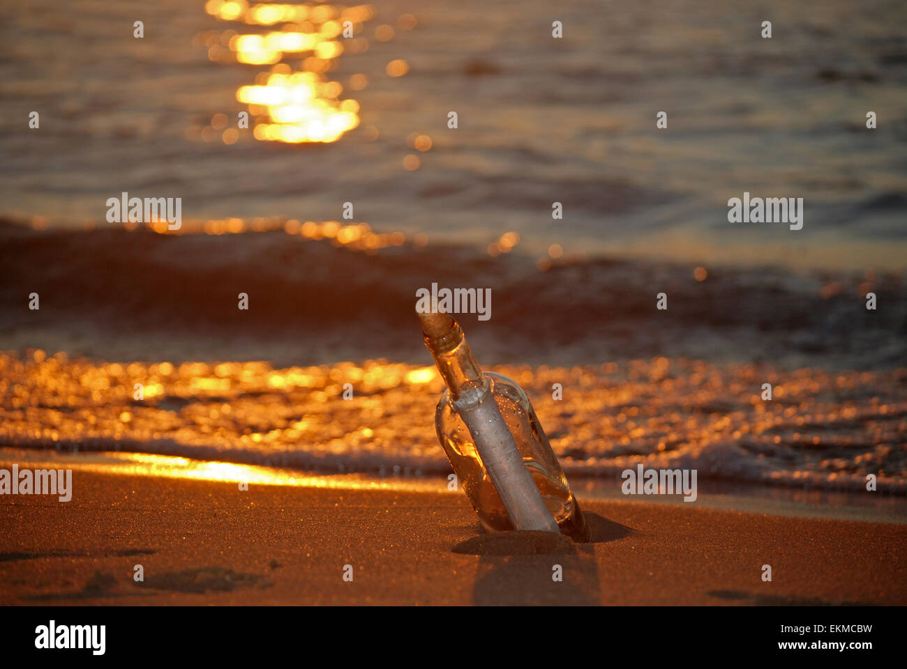 Eine Flaschenpost bei Sonnenuntergang am Strand. Stockfoto