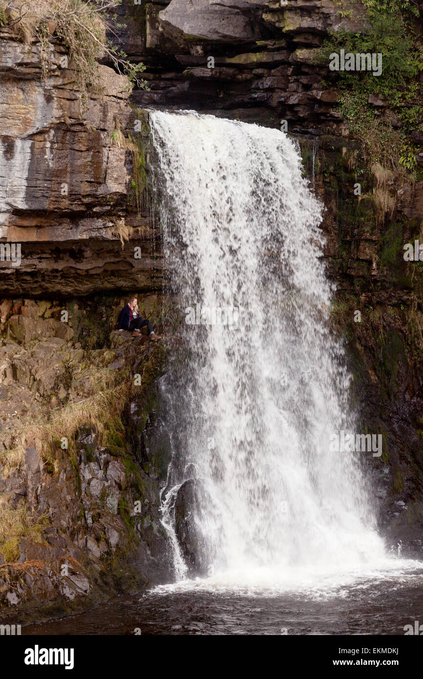 Ein junges Mädchen sitzt neben Thornton Force Wasserfall, Ingleton Wasserfälle Trail North Yorkshire Dales National Park, UK Stockfoto