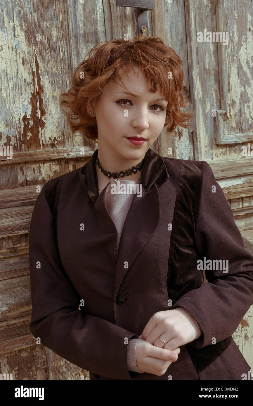 Retro-Porträt der rote behaarte Frauen in Vintage Mantel gegen veraltete hölzerne Hintergrund Stockfoto