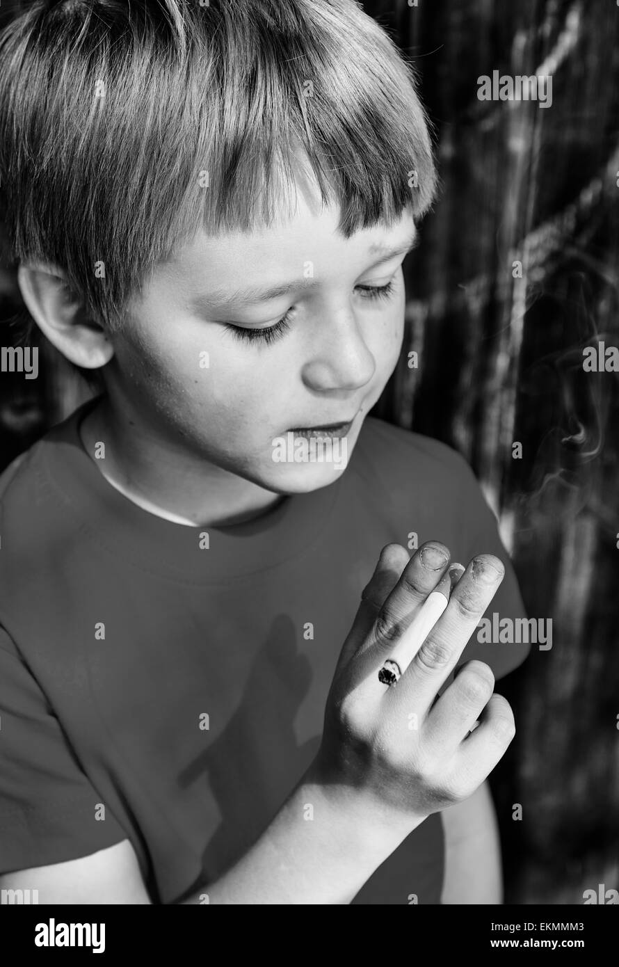 Porträt des Kindes Blondschopf qualmender Zigarette mit dunklem Holz Hintergrund hinter ihm Stockfoto
