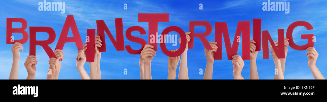 Viele kaukasische Menschen und Händen mit roten Buchstaben oder Zeichen Gebäude das englische Wort Brainstorming auf blauen Himmel Stockfoto
