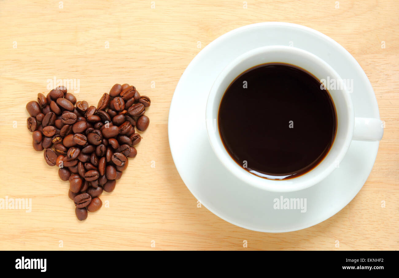 Herzform aus Kaffeebohnen mit einer Tasse Kaffee gemacht Stockfoto