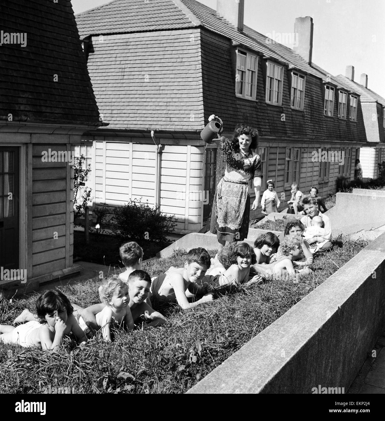 33 Jahre alte Frau Mavis Graham von Plymouth, Mutter von 13 Kindern im Alter von 4 Monaten bis 14 Jahren gibt sie alle eine Dusche mit einer Gießkanne auf dem Rasen vor ihrem Haus an einem heißen Sommertag. Devon, 1. September 1957. Stockfoto