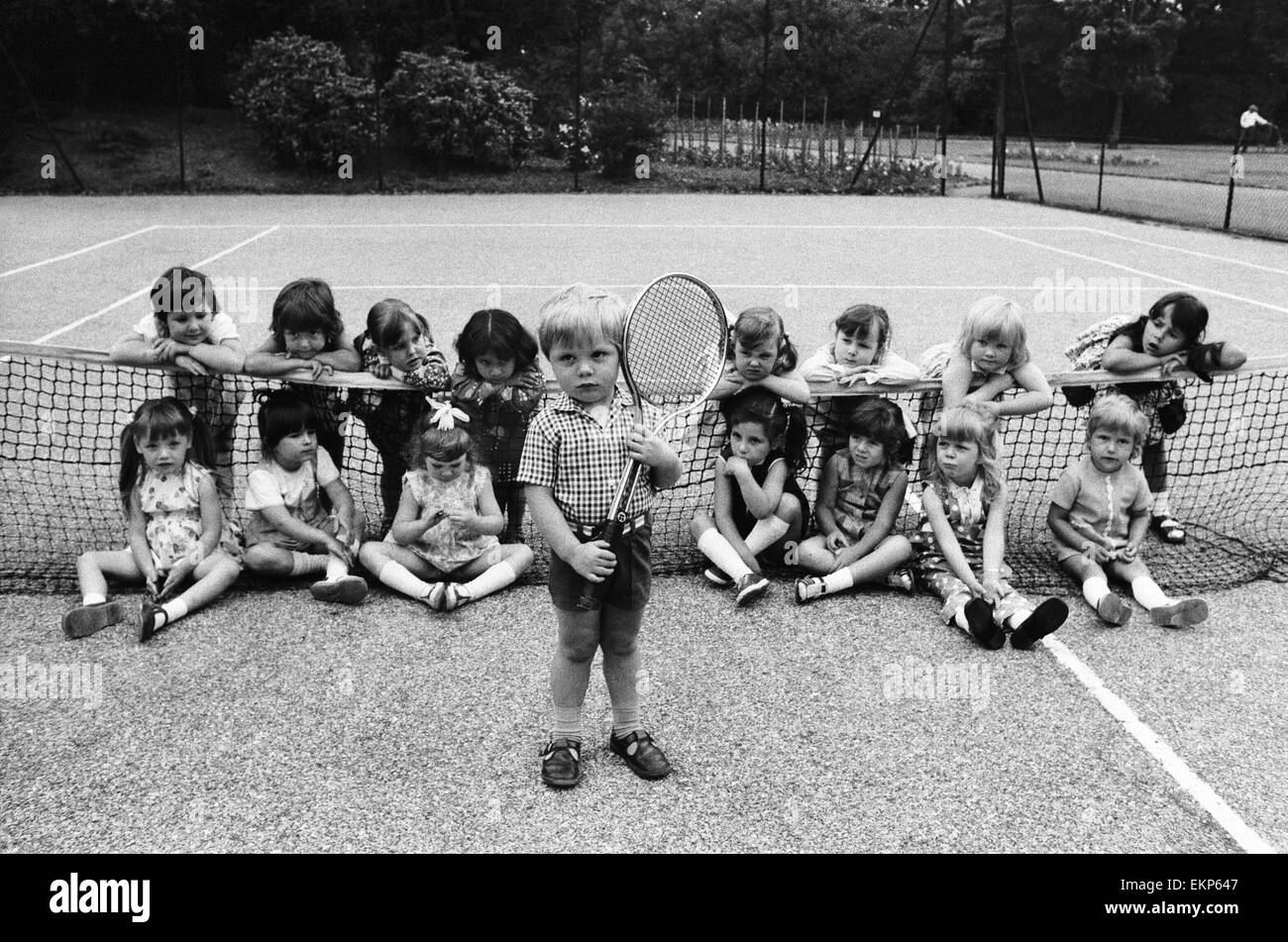 Drei Jahre alte Daniel Jarmin hält einen Tennisschläger als er mit anderen Freunden in seiner Klasse an einer Schule Kindergarten Posen besucht er in Ilford, Greater London. Daniel ist ein möglicher Wimbledon Eintrag der Zukunft. 19. Juni 1973. Stockfoto