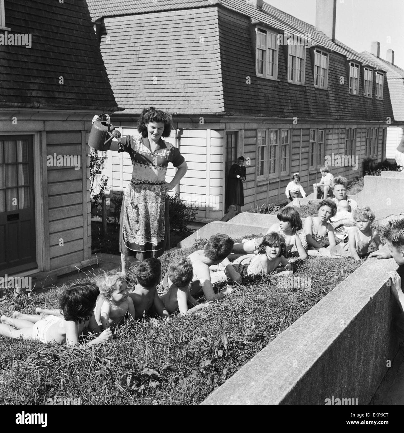 33 Jahre alte Frau Mavis Graham von Plymouth, Mutter von 13 Kindern im Alter von 4 Monaten bis 14 Jahren gibt sie alle eine Dusche mit einer Gießkanne auf dem Rasen vor ihrem Haus an einem heißen Sommertag. 1. September 1957. Stockfoto