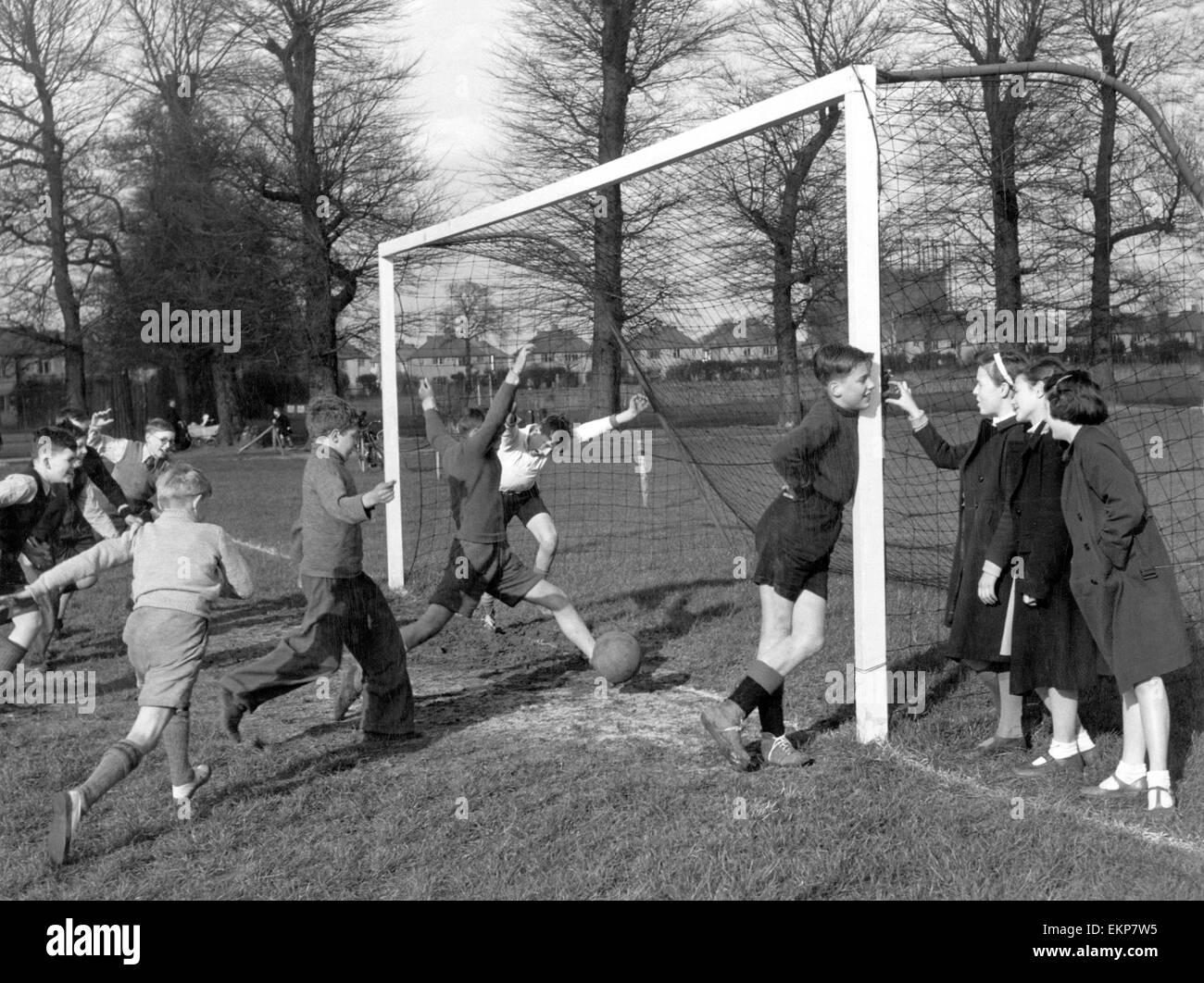 Junge Torhüter wird von einer Gruppe von Mädchen, abgelenkt, als eine,, 20. April 1951 Tor fällt. Stockfoto