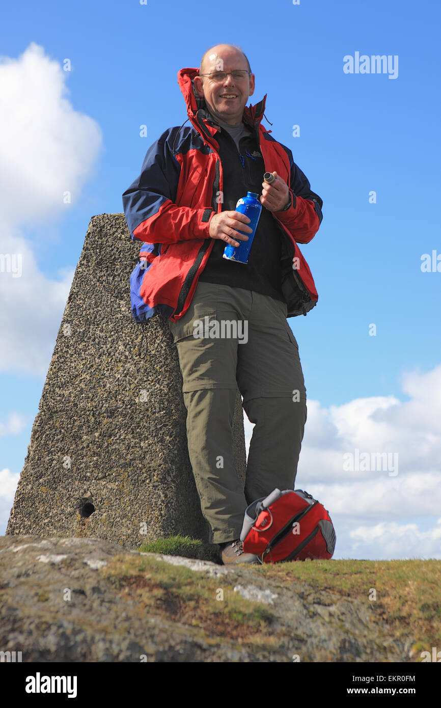 Man stützte sich auf einen trigonometrischen Punkt und nehmen einen Schluck Wasser auf dem Gipfel des Knock Hill in der Nähe von Largs in Schottland Stockfoto