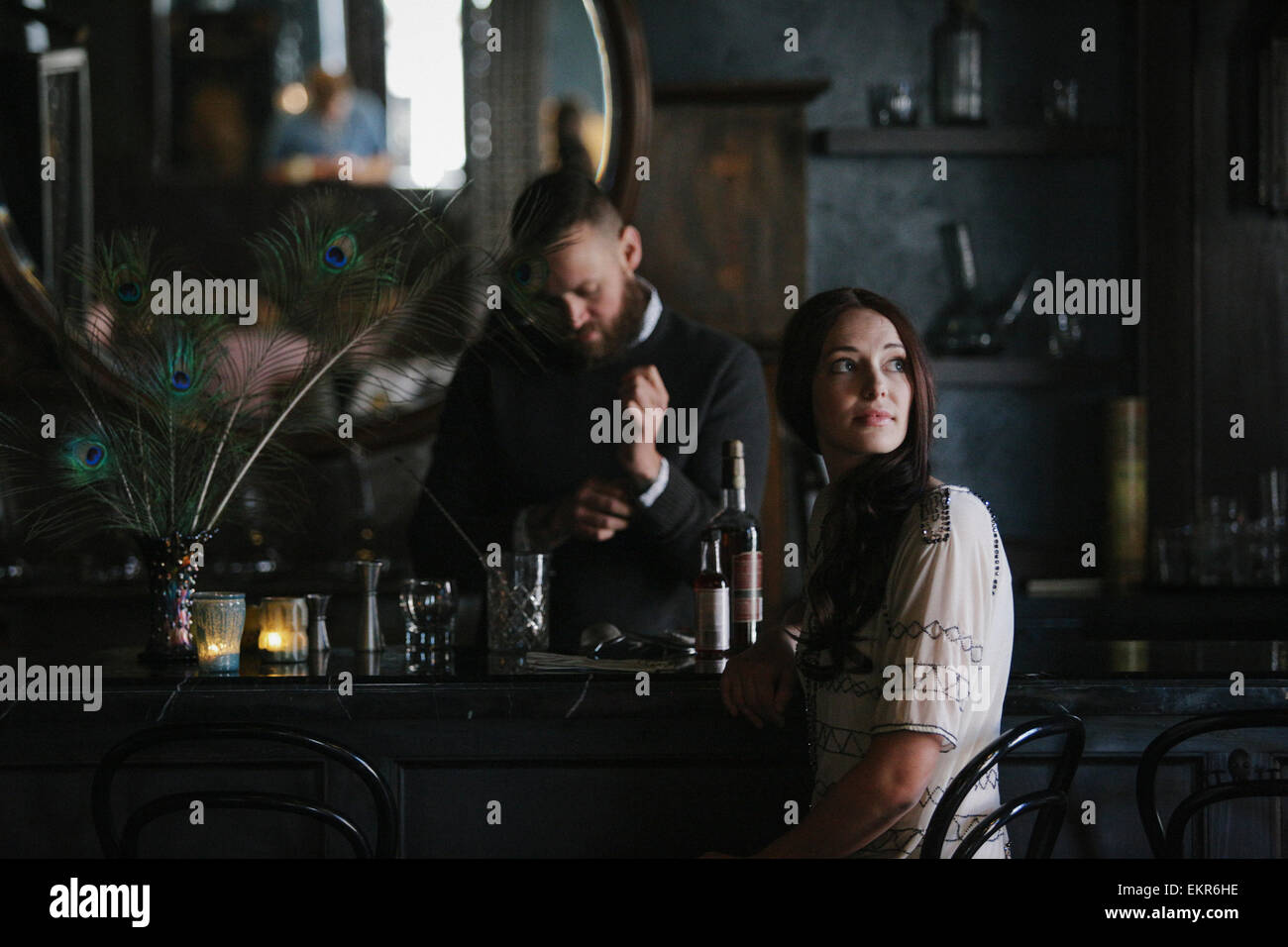 Eine Frau und ein Barkeeper sprechen, und Getränke mischen. Stockfoto