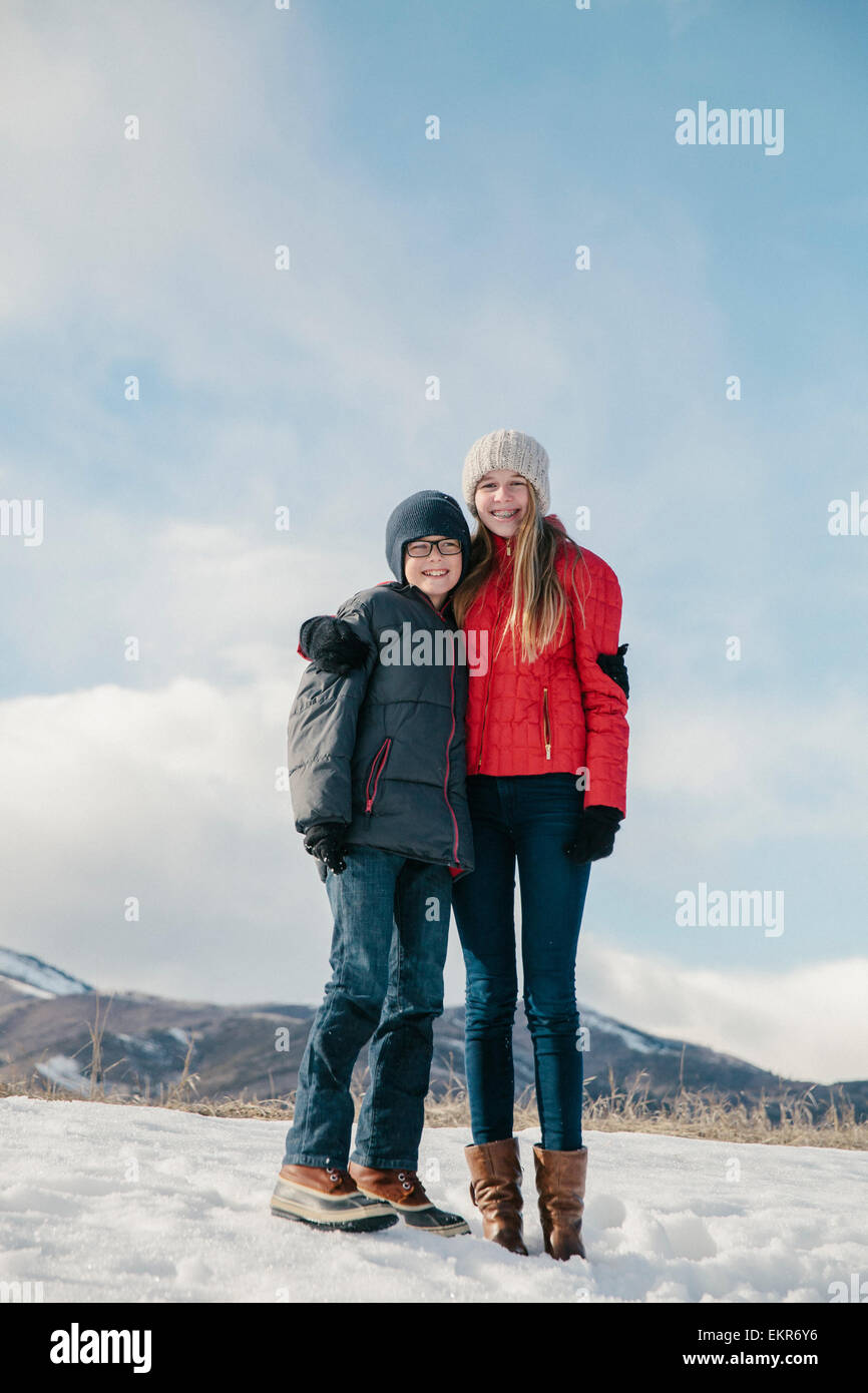 Bruder und Schwester nebeneinander im Schnee stehen. Stockfoto