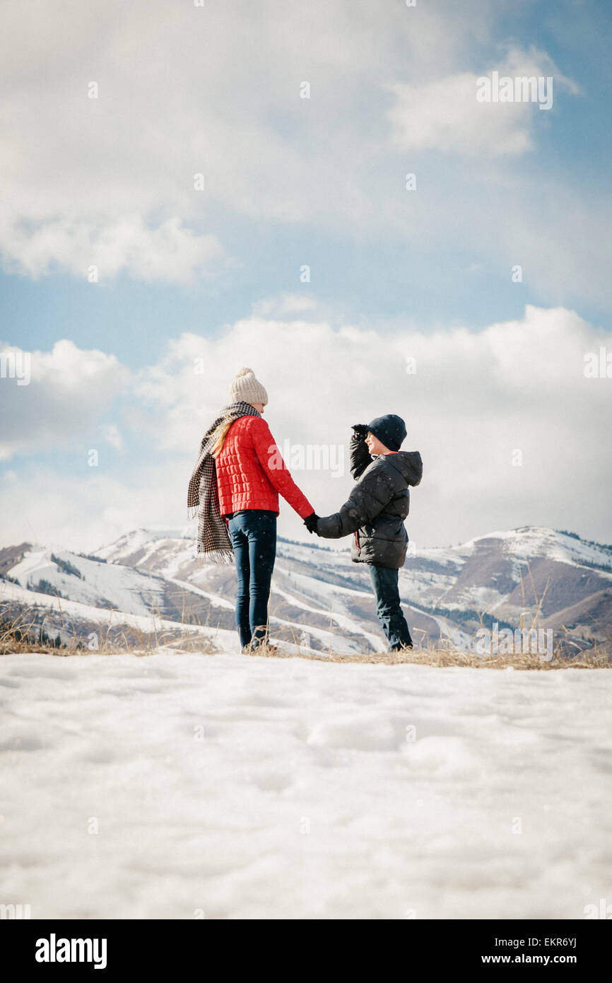 Bruder und Schwester Hand in Hand und mit Blick auf die verschneite Landschaft. Stockfoto