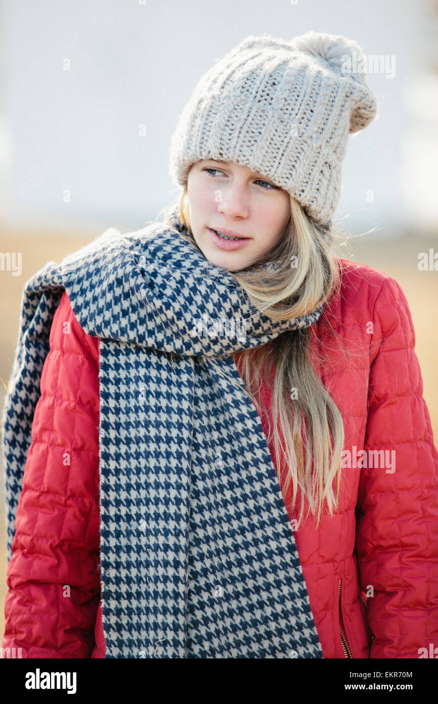 Ein Mädchen in einer roten Jacke mit einem großen aufgegebenen wollenen Schal. Stockfoto