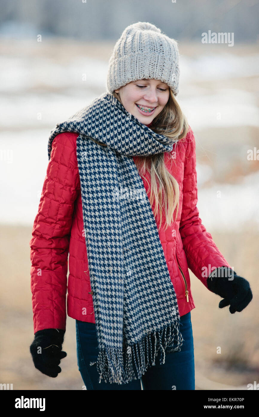 Ein Mädchen in einer roten Jacke mit einem großen aufgegebenen wollenen Schal. Stockfoto