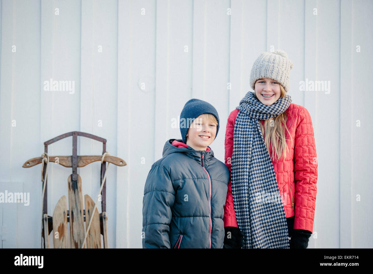 Bruder und Schwester nebeneinander in einem Hof im Winter. Stockfoto