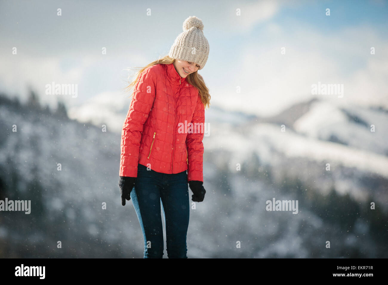 Ein junges Mädchen in einem roten Mantel und Wollmütze im Freien im Winter. Stockfoto