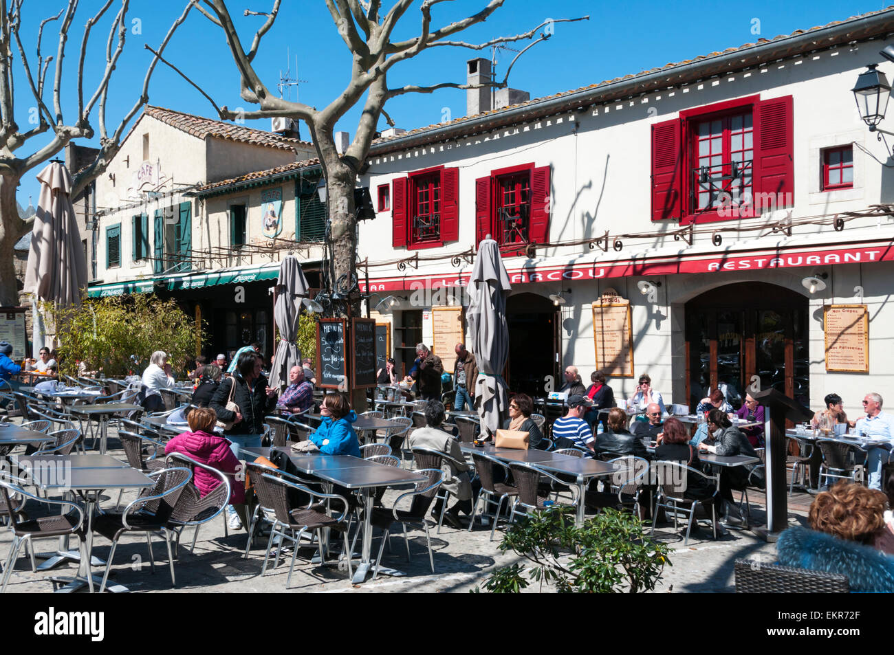 Personen an Tischen vor Le Marcou Restaurant im Ort Marcou in der Cité, die alten Mauern umgebene Stadt Carcassonne. Stockfoto