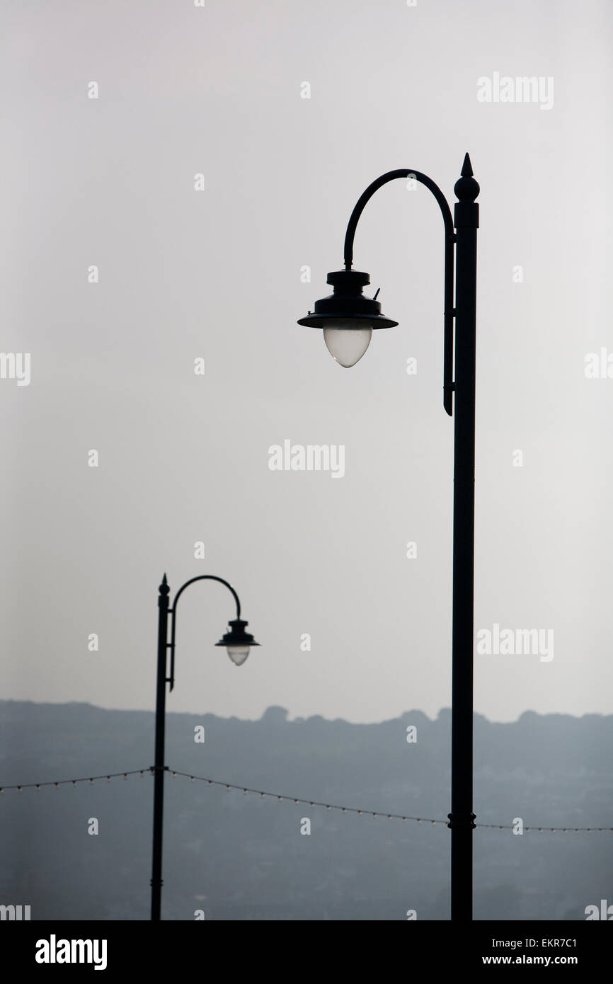 Zwei gewölbte Straßenlaternen Silhouette gegen einen grauen Himmel. Stockfoto