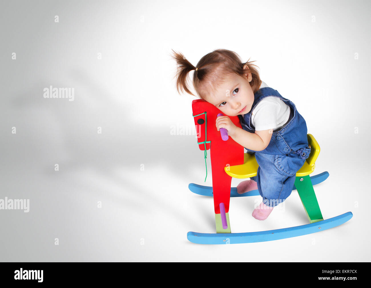 lustige träumendes kleine Mädchen reitet Spielzeugpferd Stockfoto