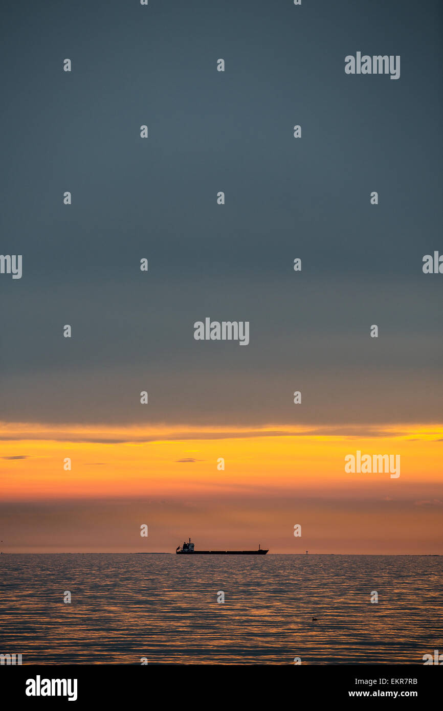 Ein Schiff in den Sonnenuntergang aus Triest, eine Stadt im Nordosten Italiens an der Adria. Die Stadt ist ein geschäftiger Hafen Stockfoto