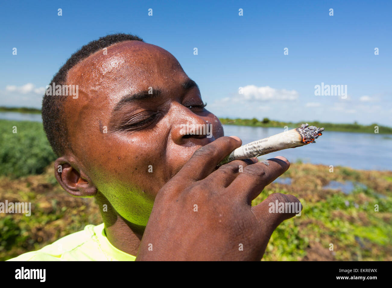 Ein Mann Rauchen lokal angebaute Cannabis in einem Roll-up Spliff in Nsanje, Malawi. Stockfoto
