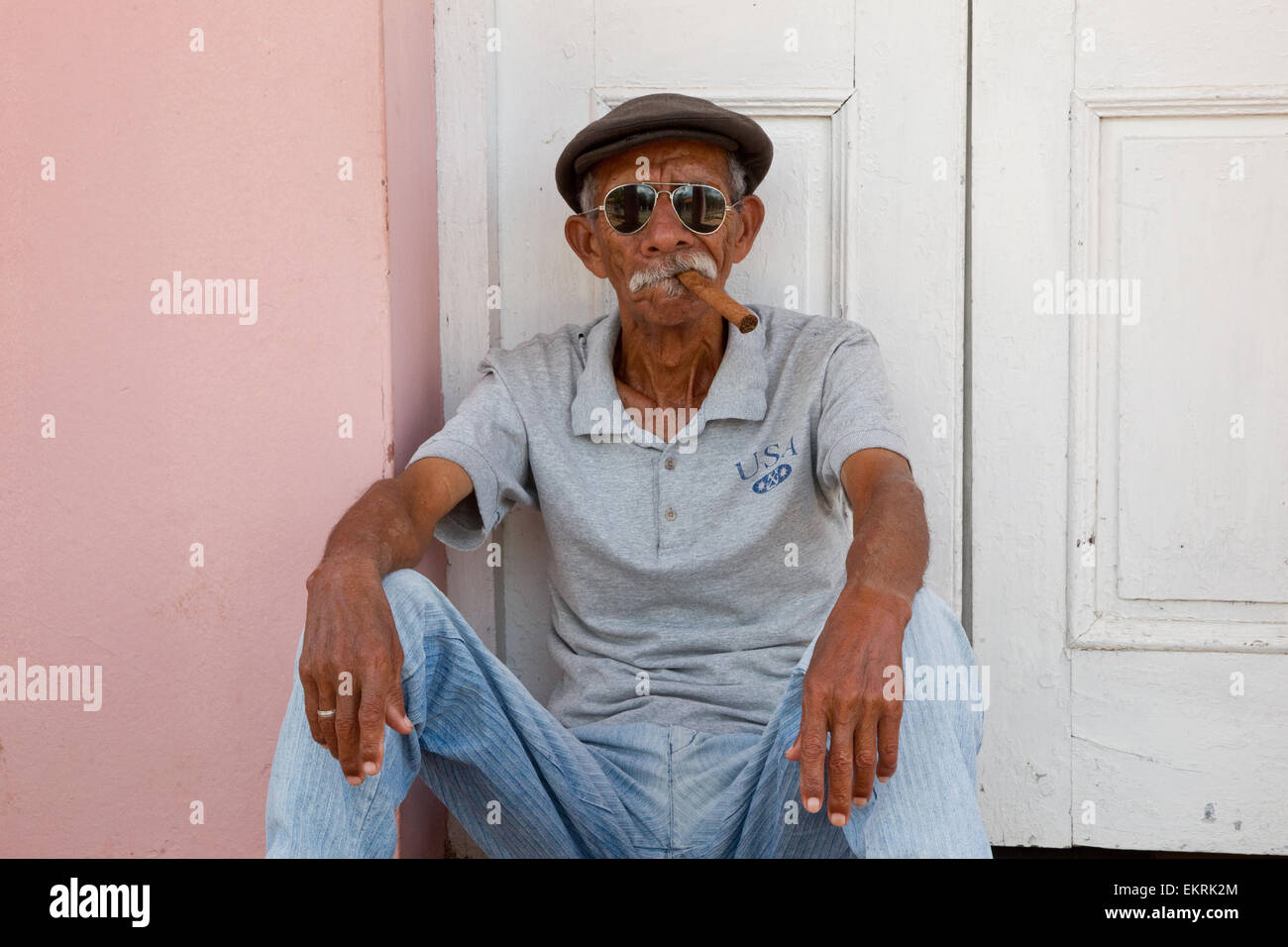 Kubanische Mann mit Sonnenbrille, raucht eine Zigarre in einem Hauseingang Stockfoto