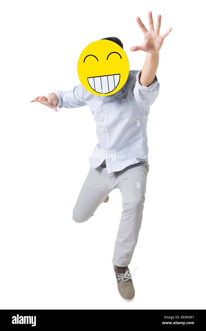 Junger Mann läuft mit einem glücklichen Emoticon Gesicht vor seinem Gesicht Stockfoto