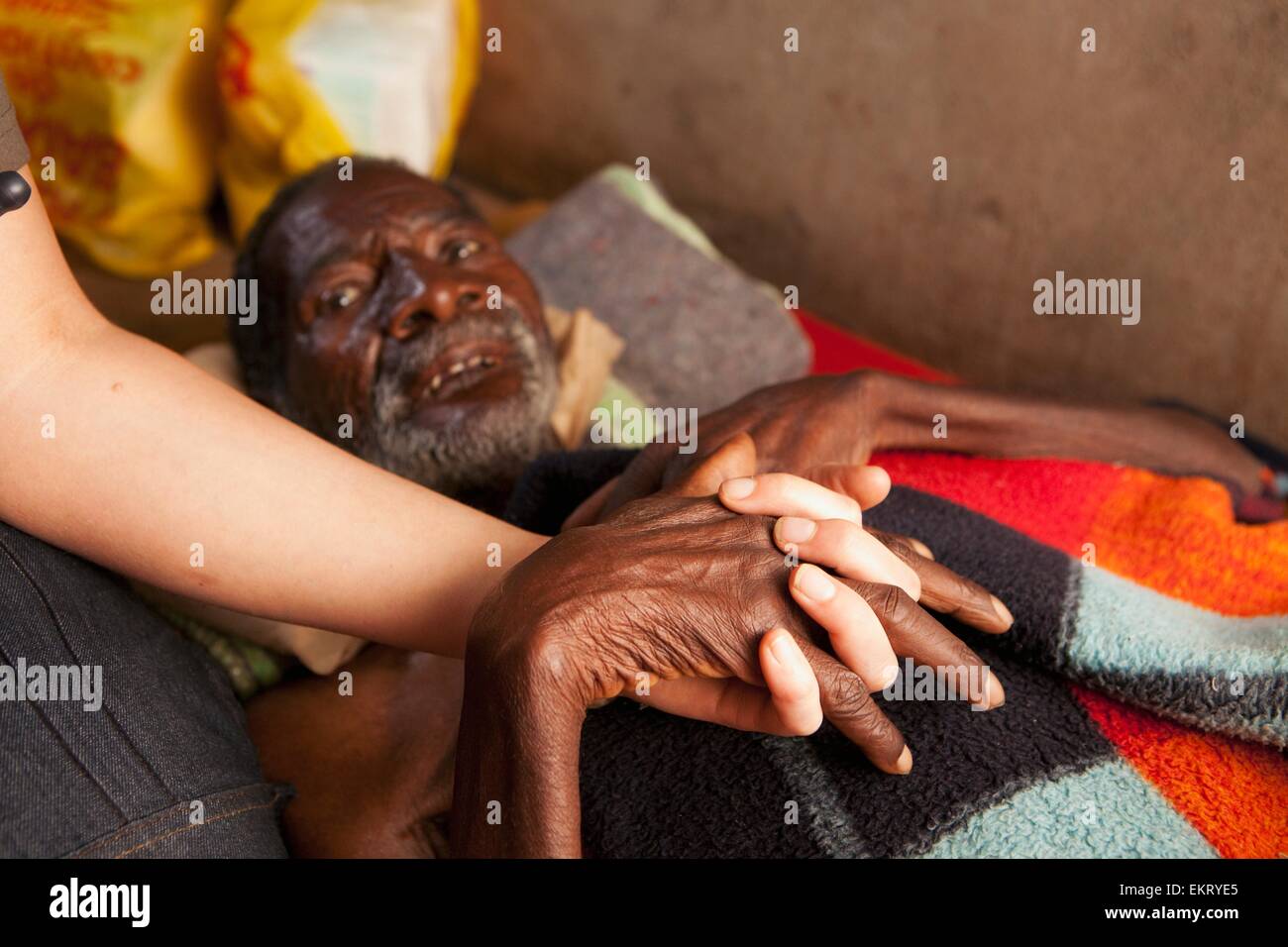 Eine Krankenschwester hält die Hand eines Menschen sterben an einer Lungenentzündung; Manica, Mosambik, Afrika Stockfoto