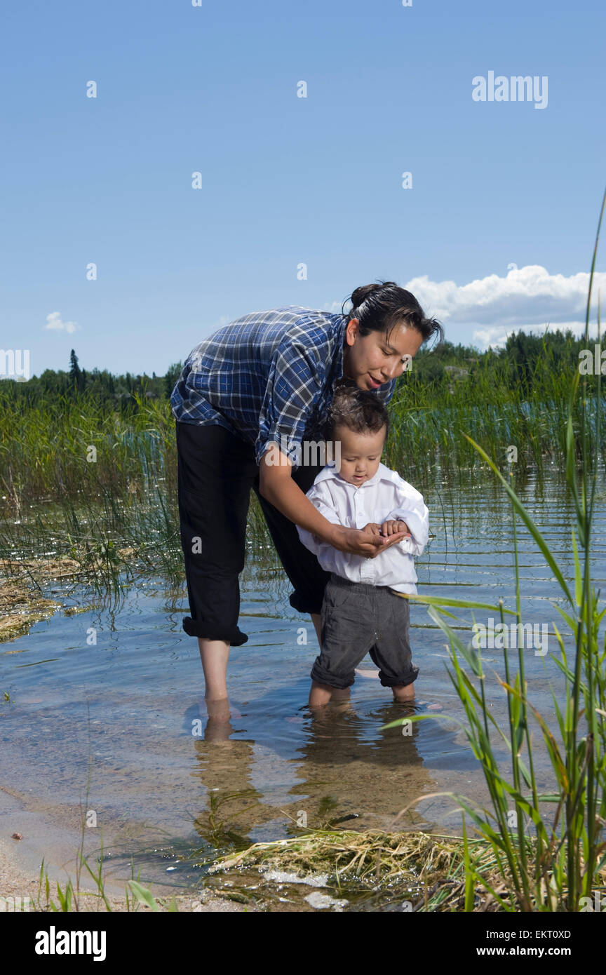 Native American Mutter und ihr Sohn stehen im flachen Wasser der Untiefe See, Ontario, Kanada Küstenlinie. Stockfoto