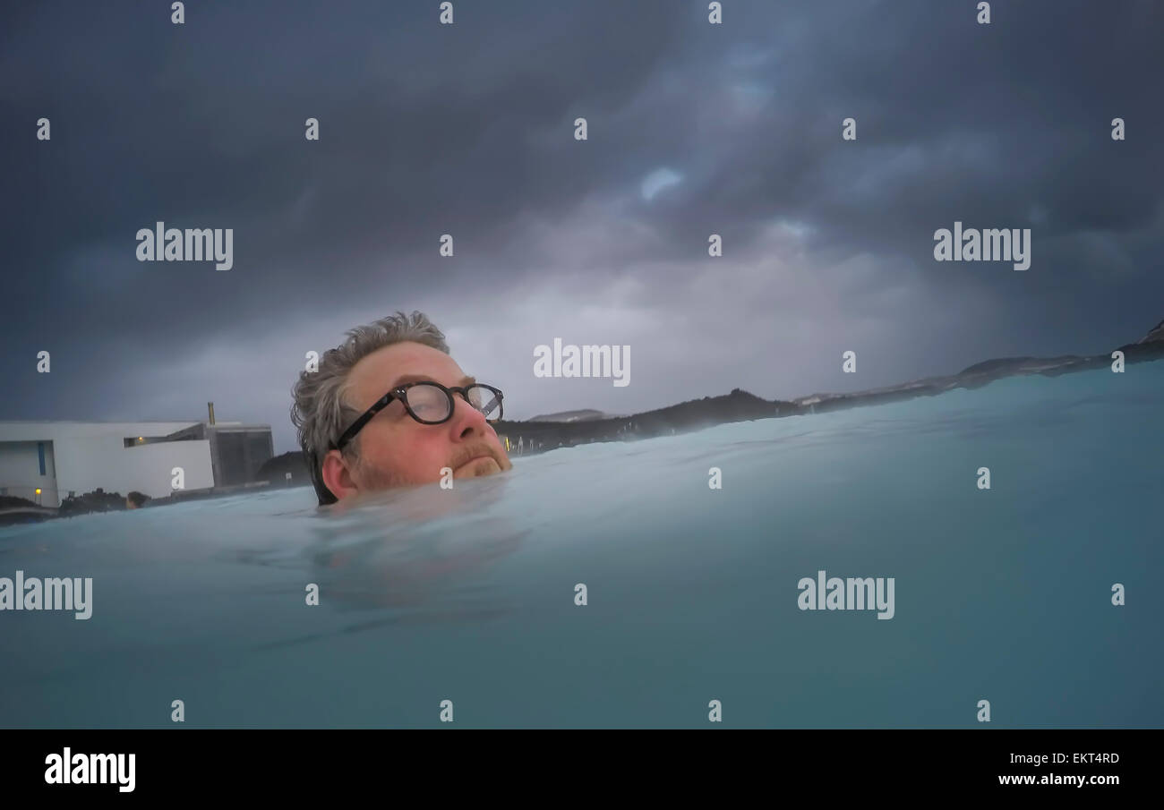 Mann mit Brille in der blauen Lagune, geothermische Baden heiße Quellen, Island Stockfoto
