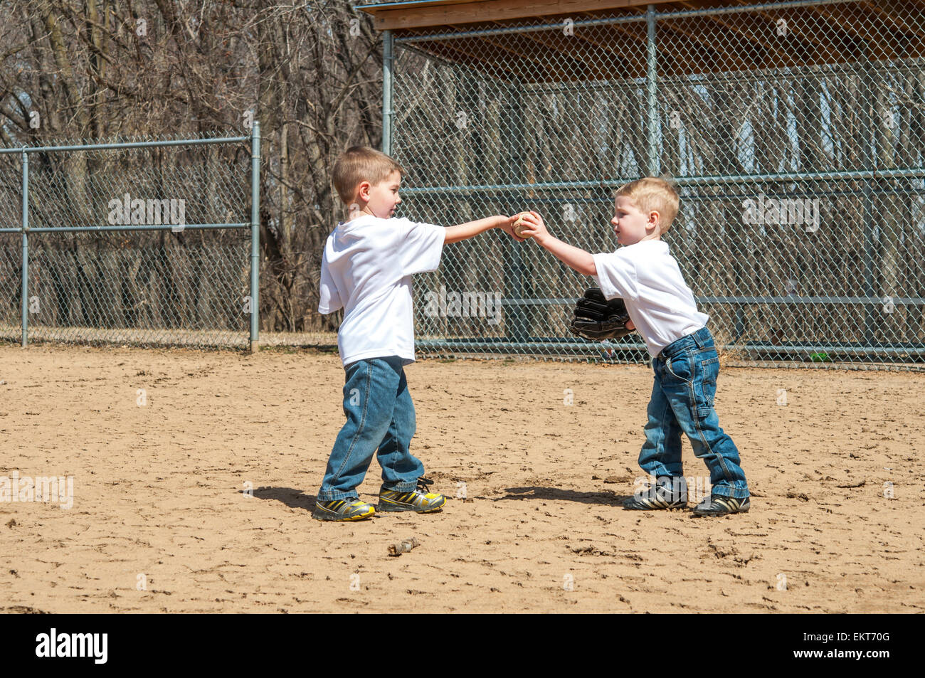 Zwei Jungs geben einander einen Baseball auf Feld Stockfoto