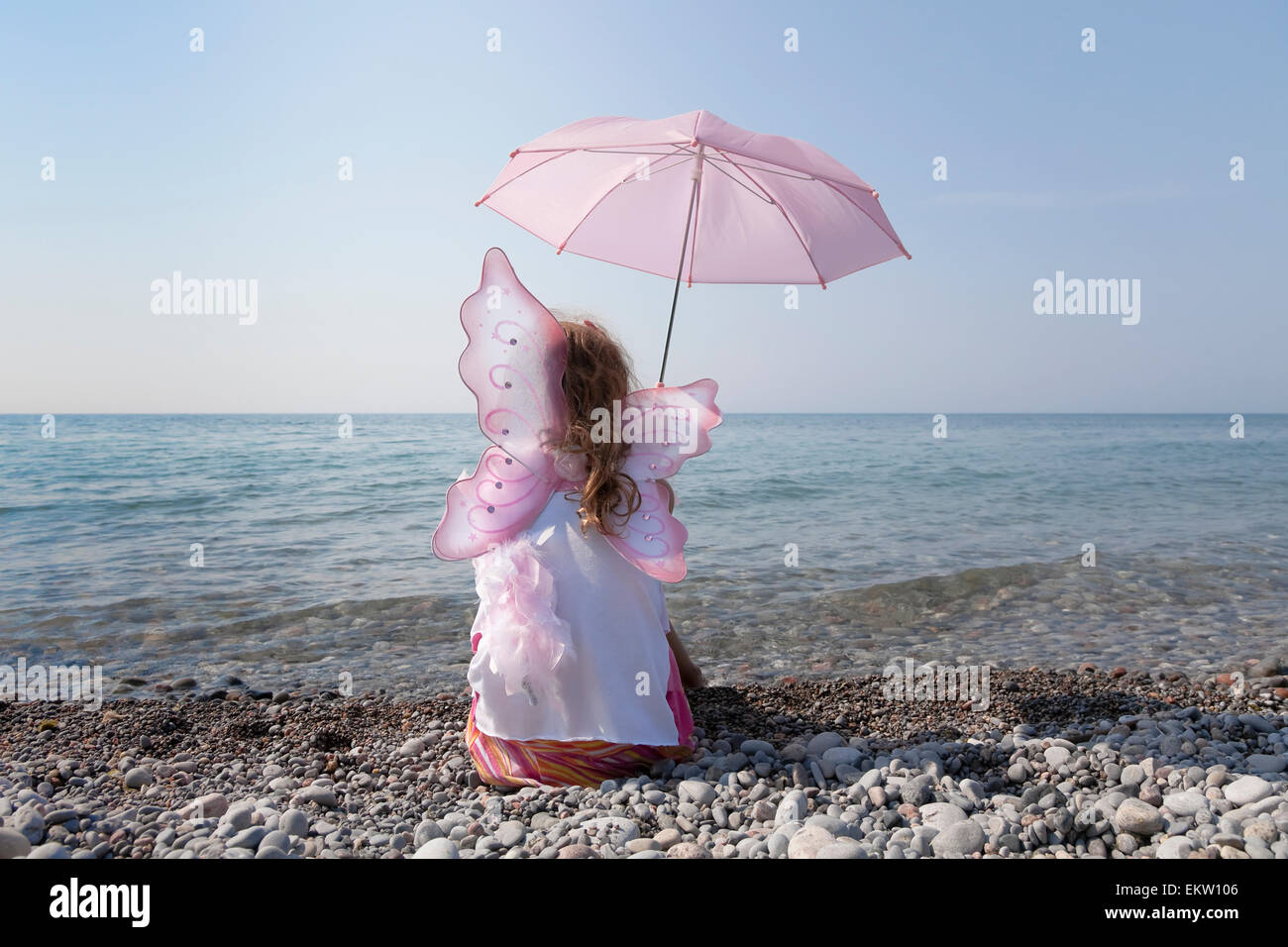 Junges Mädchen mit rosa Sonnenschirm und tragen Feenflügel am Ufer des Lake Ontario; Whitby, Ontario Kanada Stockfoto