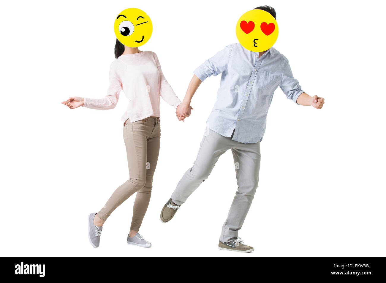 Junges Paar mit Cartoon Emoticon steht vor den Gesichtern Stockfoto